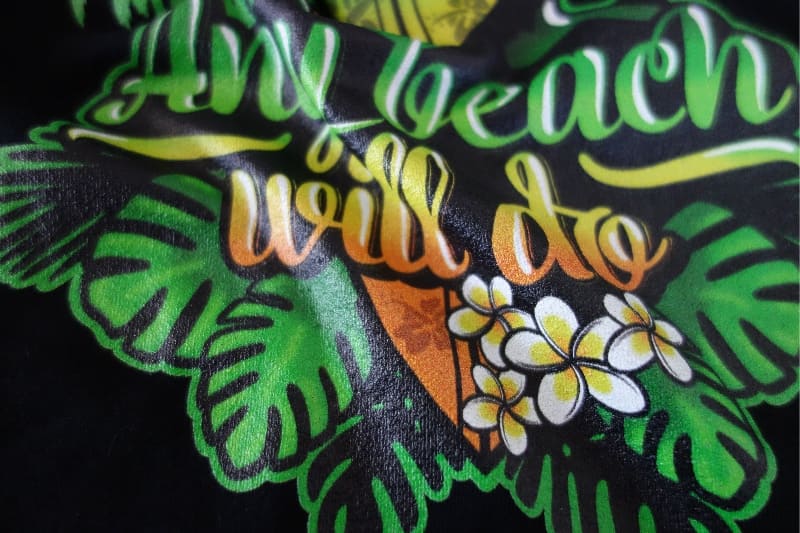 Waving black t-shirt with a beach motiv print on.