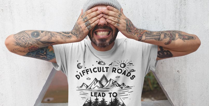 A guy wearing a white t-shirt and covering his face with both hands. DTG printing pros and cons blogpost.